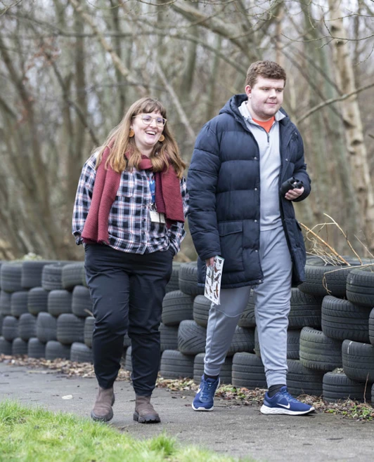 Young man and woman walking along a path lined with stacked tires, smiling and enjoying the outdoor walk. Young man and woman walking along a path lined with stacked tires, smiling and enjoying the outdoor walk.